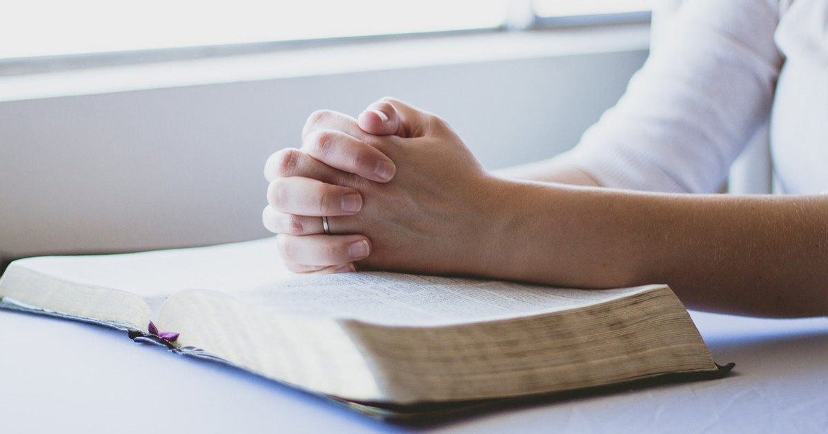 mani unite in preghiera su bibbia